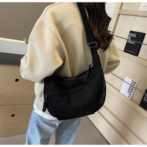 Close-up of black corduroy hobo bag featuring woven rope zipper and adjustable strap