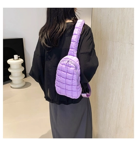 Detailed back view of a purple quilted nylon crossbody bag worn on a model in a modern room