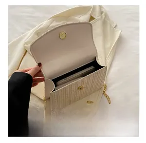Detail view of woven straw crossbody bag with golden magnetic clasp and chain strap