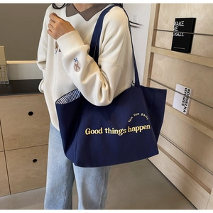 Detailed macro view of the dark blue canvas tote bag featuring yellow fun party lettering