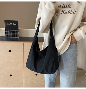 Bolso hobo grande minimalista de nailon negro llevado por una modelo para el estilo diario