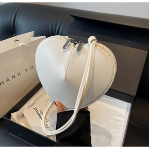 Dettaglio borsa bianca a forma di cuore in pelle con doppia cerniera in metallo argentato