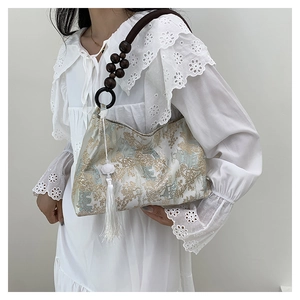 Detail of fabric handbag with mountain pattern, wooden bead handle and long white tassel
