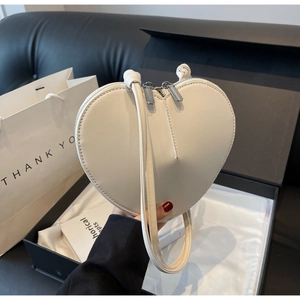 Dettaglio della borsa in pelle color crema a forma di cuore con doppia cerniera e cucitura
