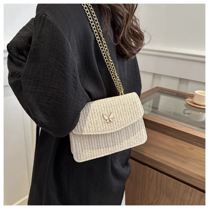 Detailed close-up of cream woven fabric texture and white butterfly buckle on a crossbody bag