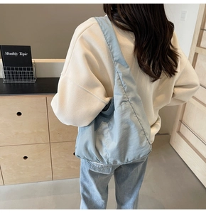 Vista trasera de una modelo con un bolso hobo suave de nailon azul claro sobre el hombro