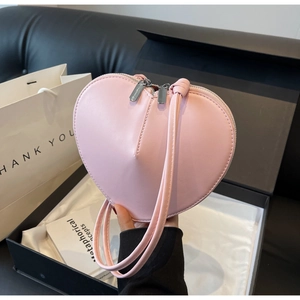 Dettaglio di borsa in pelle rosa a forma di cuore esposta in una scatola regalo di lusso
