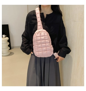 Detail of pink quilted puffer crossbody bag with dual metal zippers and nylon fabric texture