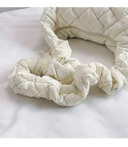 Close-up of cream nylon cloud bag featuring colorful diamond quilting and ruffled strap