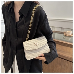 Close-up of white woven crossbody bag with butterfly clasp and gold chain strap