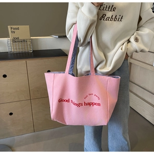 Close-up of pink canvas tote bag with lettering and blue striped inner lining