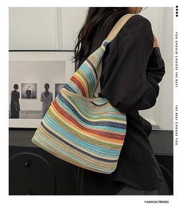 Chic knit tote with colorful stripes and leather shoulder strap shown on a model