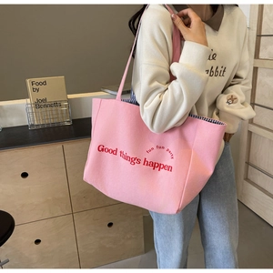 Pink canvas tote bag with red typography and striped lining shown on a female model