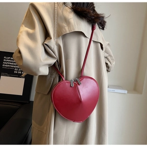 Primo piano di una borsa a tracolla rossa a forma di cuore in pelle PU con zip in metallo