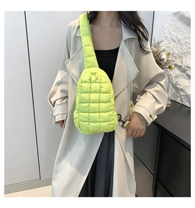Detail of neon yellow quilted nylon crossbody bag with dual zippers worn by a model