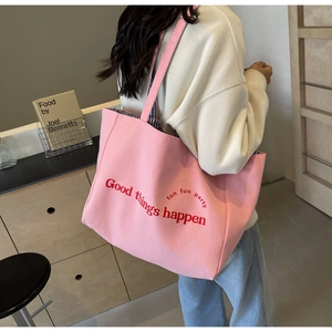 Detail of pink canvas tote bag showing 'Good things happen' text and striped lining