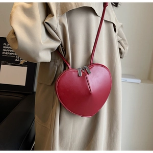 Dettaglio della borsa a tracolla a forma di cuore rossa in pelle con zip argentate