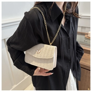 Detail of woven fabric texture and gold butterfly clasp on beige crossbody bag