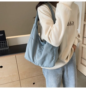 Detalle del bolso de tela azul claro con práctico bolsillo frontal y textura suave al tacto