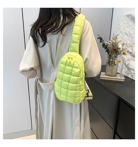 Detail of neon yellow quilted nylon crossbody bag with grid pattern on a beige coat