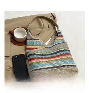 Close-up of knit tote bag with colorful horizontal stripes and brown leather handles