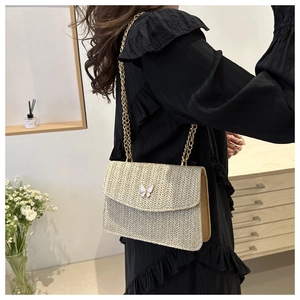 Close-up of woven straw texture and butterfly buckle on beige crossbody bag