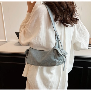 Detail of light blue denim shoulder bag featuring side pockets and adjustable strap for women