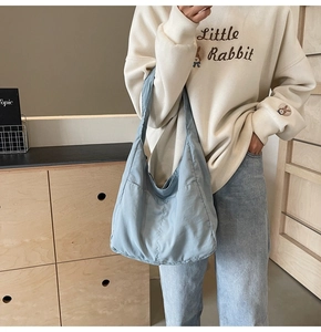 Detalle del bolso hobo de lona azul claro con bolsillos laterales y textura minimalista
