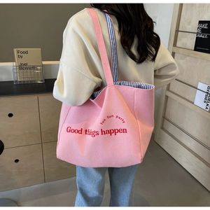 Pink canvas tote bag with Good Things Happen embroidery shown in a cozy home setting