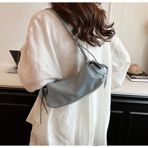 Detail view of grey-blue fabric crossbody bag with adjustable drawstring on a model