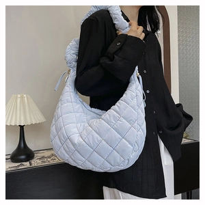 Detail of light blue quilted nylon hobo bag with padded shoulder strap on female model