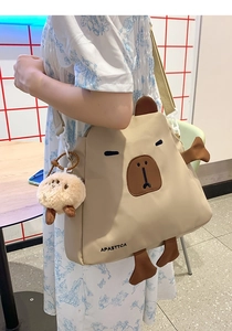 Vue détaillée d'un joli sac bandoulière capybara beige en nylon porté dans un café