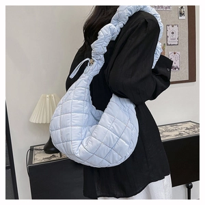 Detail of light blue quilted nylon shoulder bag with ruffled strap and grid pattern