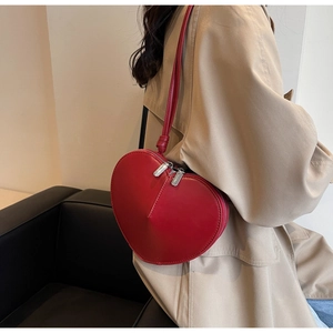 Dettaglio di una borsa a tracolla rossa a forma di cuore indossata da una modella