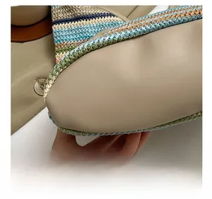 Detail shot of the precise stitching connecting woven patterns and beige leather on the bag