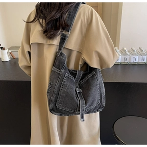 Close-up of black washed denim crossbody bag with contrast white stitching and wide strap