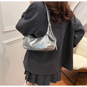 Silver metallic shoulder bag with pleated design and adjustable strap on a model