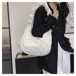 Detail of white quilted nylon crossbody bag featuring ruffled strap and tassel accent