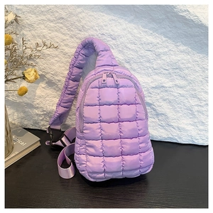 Quilted lavender nylon crossbody bag with adjustable strap on a textured rock background