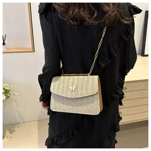 Detail of beige woven crossbody bag with a delicate white metal butterfly buckle