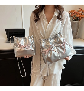 Détail de sacs argentés métallisés en deux tailles avec nœud rose et bandoulière chaîne