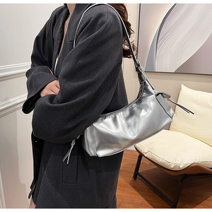 Detail view of silver metallic shoulder bag with drawstring texture on model in gray blazer
