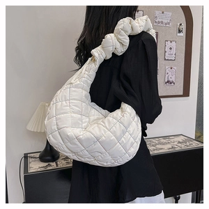 Close-up of a white quilted nylon puffer tote bag with colorful stitching and scrunchie strap