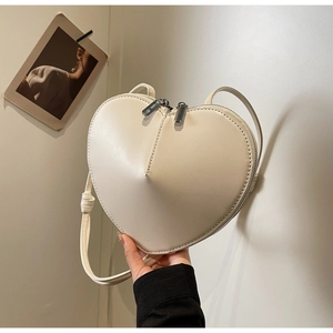 Dettaglio della borsa a tracolla a forma di cuore color crema con doppia zip in metallo