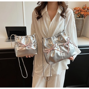 Détail des sacs à cordon en argent métallique en deux tailles avec nœuds roses décoratifs