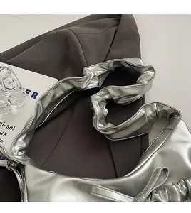 Close-up of a silver metallic ruched PU leather crossbody bag on a grey blazer garment