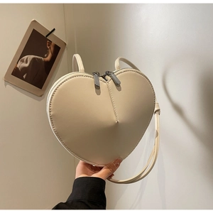 Dettaglio di una borsa a cuore color crema in pelle PU con doppia cerniera in metallo