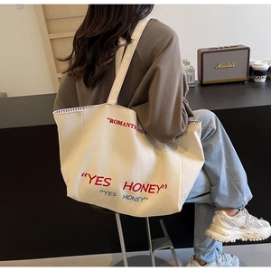 Detail shot of off-white canvas tote with blue and red embroidery in vintage style