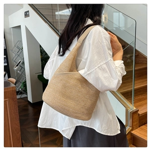 Detail of handwoven beige straw bucket bag featuring premium leather strap and texture