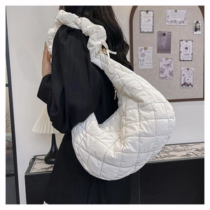 Detailed shot of white quilted crescent bag showing colorful stitching and puffy strap